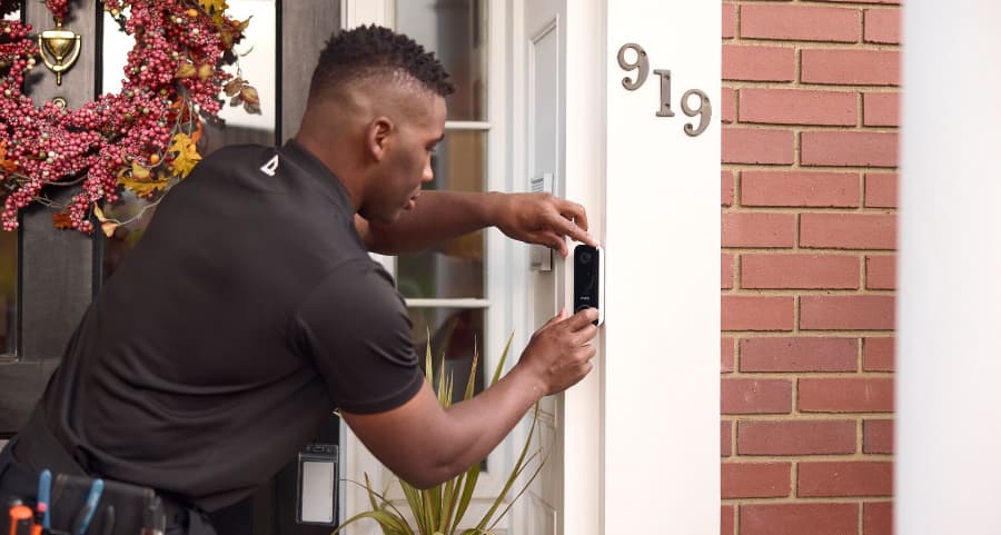 Vivint tech installing a video doorbell at the front of a home